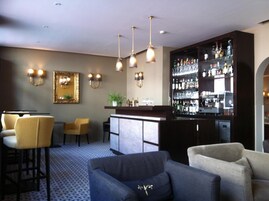 Uma área de bar com balcão, banquetas e uma parede de garrafas de bebidas.