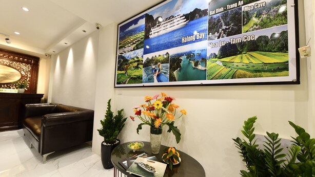 Ein Empfangsbereich mit einem großen Poster von Reisezielen, einem Ledersofa, einem Glastisch mit Blumenvase und Topfpflanzen.