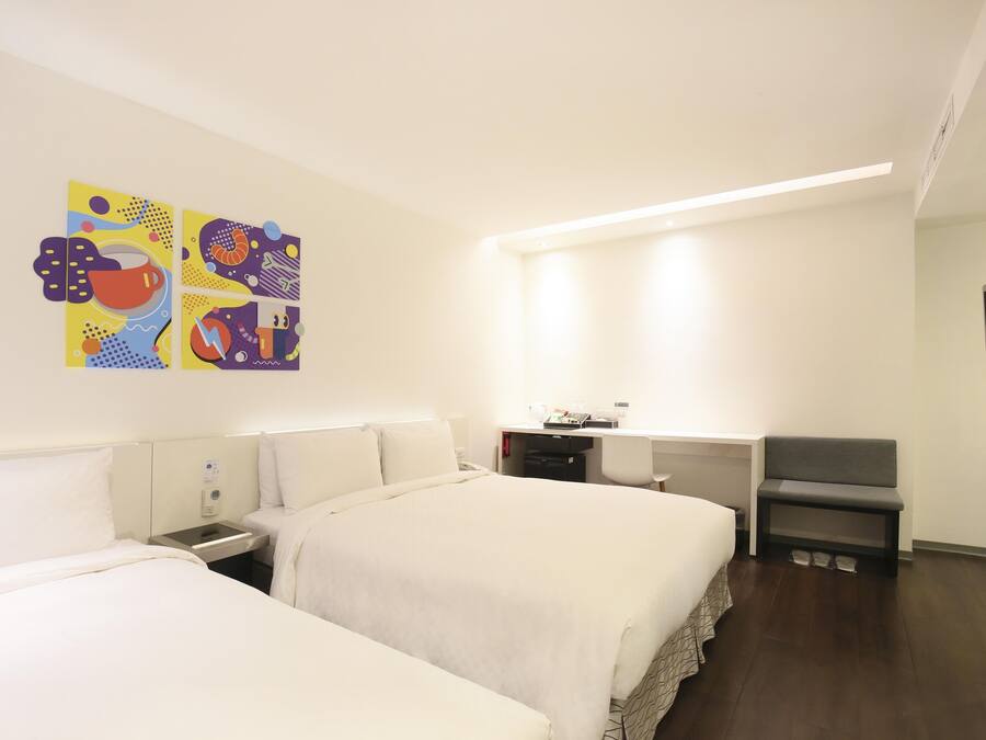Habitación de hotel con dos camas, un escritorio, una silla y un televisor.