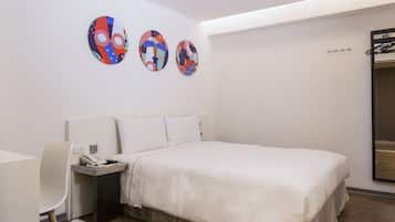 Habitación de hotel con cama, escritorio y silla. Seis adornos circulares decoran la pared.