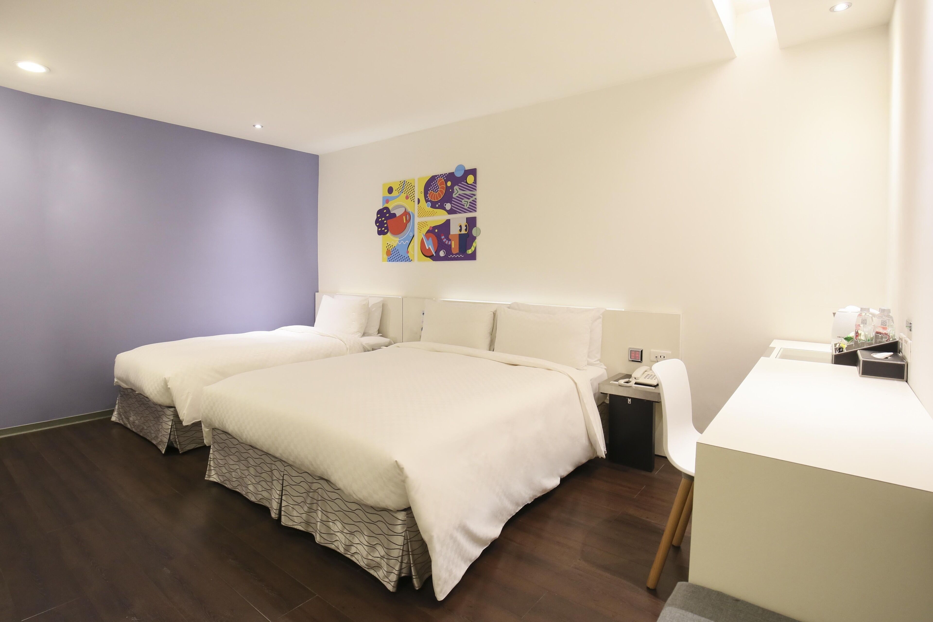 A modern hotel room with two beds, a desk, and a chair.