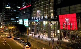 Een modern gebouw met grote glasramen en een opvallend rood bord.
