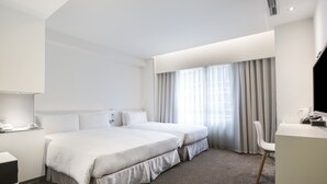 Une chambre d’hôtel avec deux lits, un bureau et une chaise.