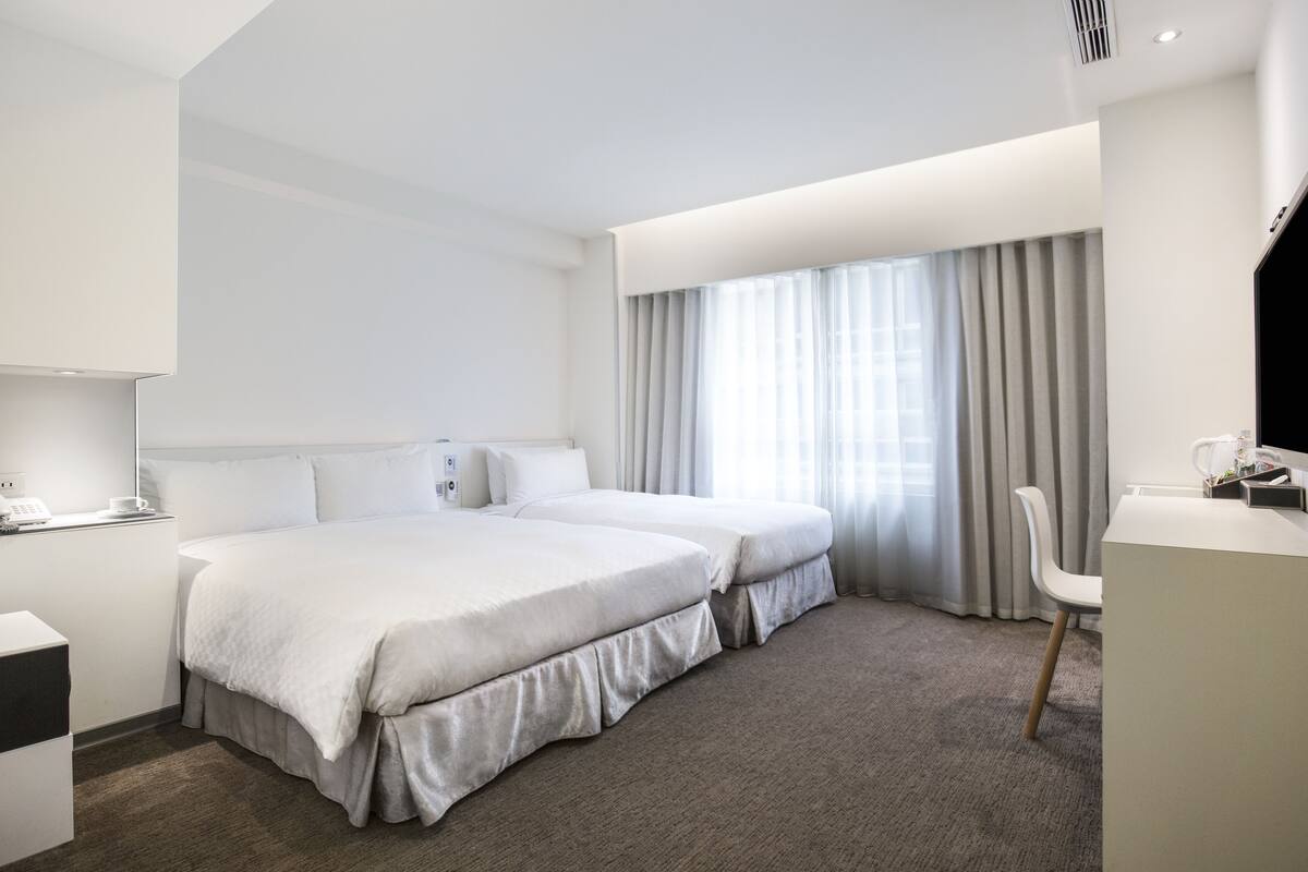 Una habitació d'hotel moderna amb un llit gran, una taula de treball i una cadira.