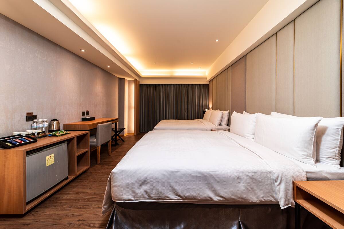 Una camera d'albergo con un letto grande, una scrivania, un minibar e una zona relax.