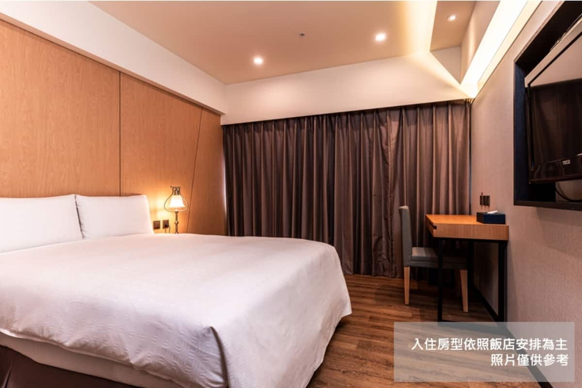 Una camera d'albergo con un letto grande, una scrivania e una sedia.