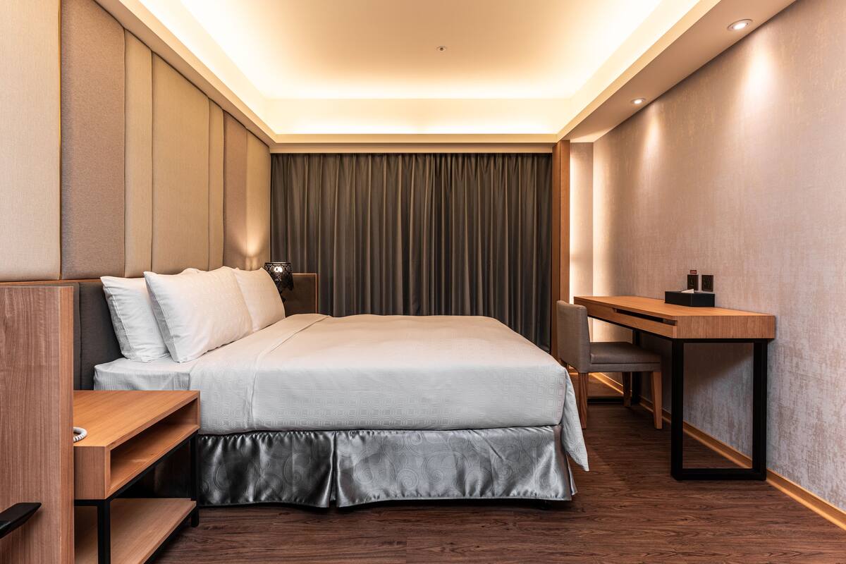 Una camera d'albergo moderna con un letto grande, una scrivania e una sedia.