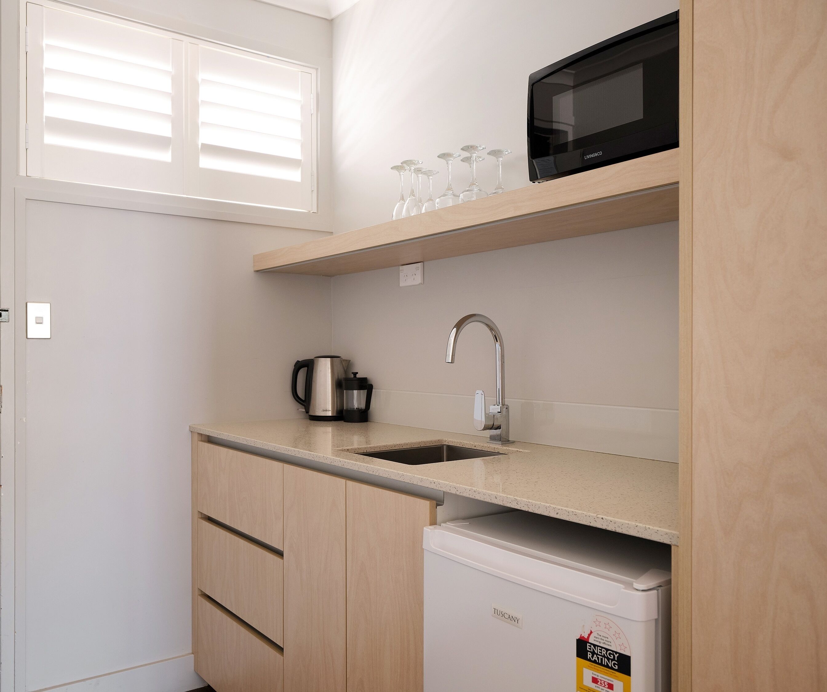 A compact kitchen with a microwave, kettle, and sink.