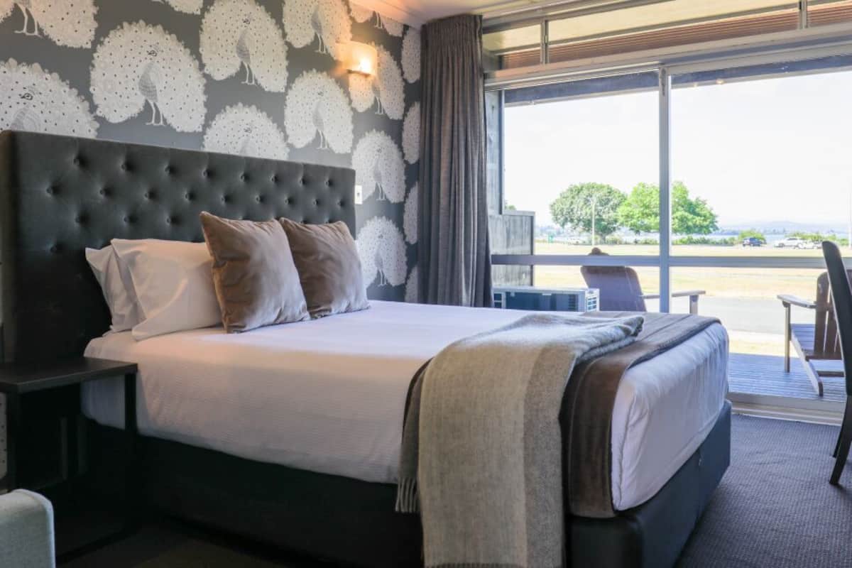 Een hotelkamer met een groot bed, een nachtkastje, een bureau en uitzicht op de omgeving.