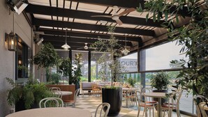 Un café con terraza, macetas y vista a la calle.
