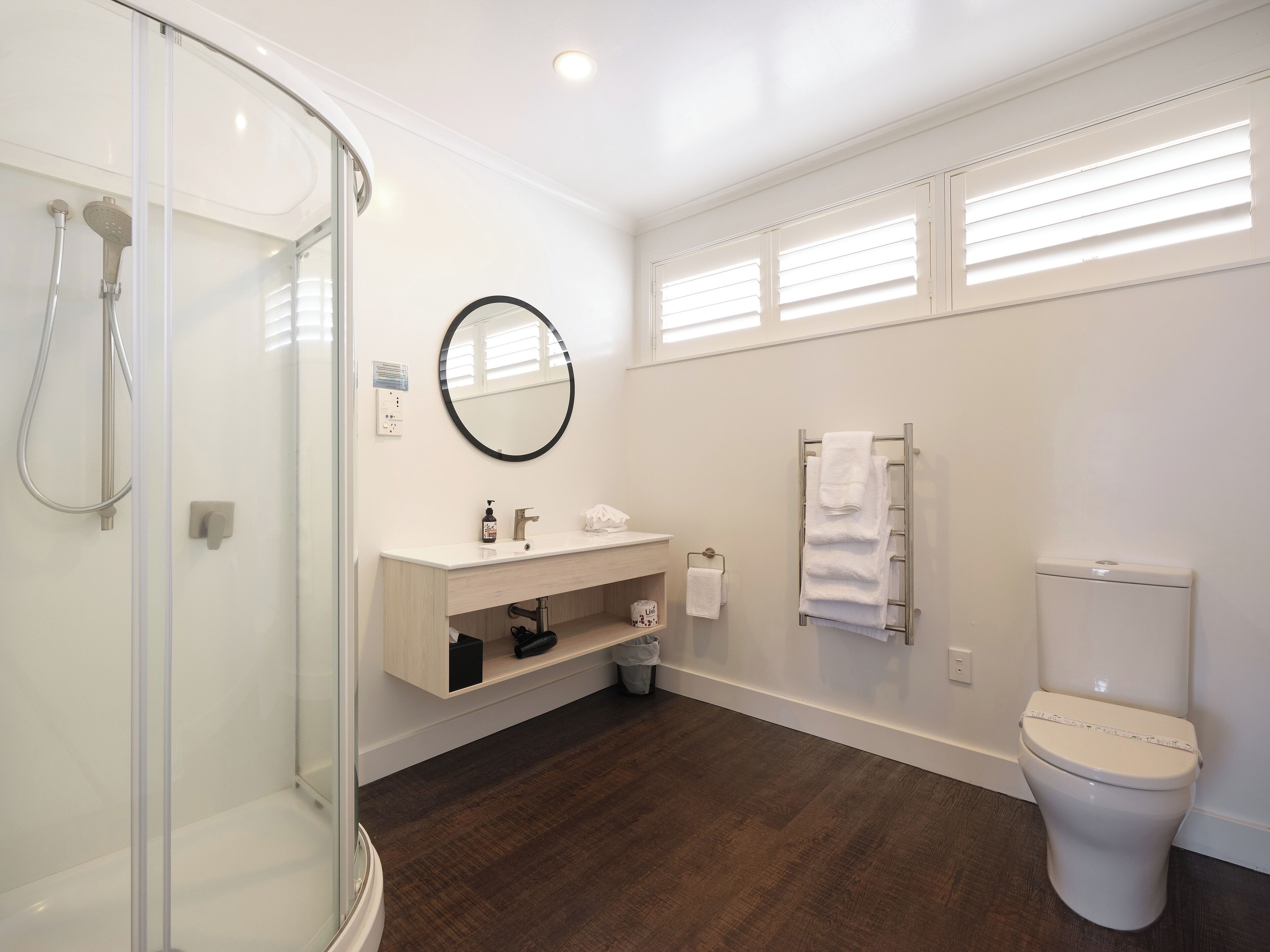 Un bagno moderno con box doccia in vetro, lavabo bianco con specchio, water e porta asciugamani.
