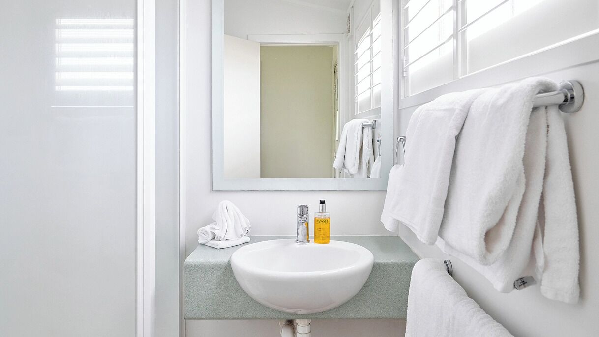 A bathroom with a white sink, a mirror, and a towel rack.