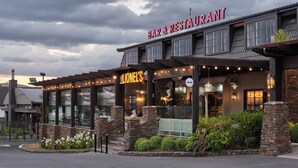 Un bar y restaurante con fachada de piedra, amplias ventanas y terraza.