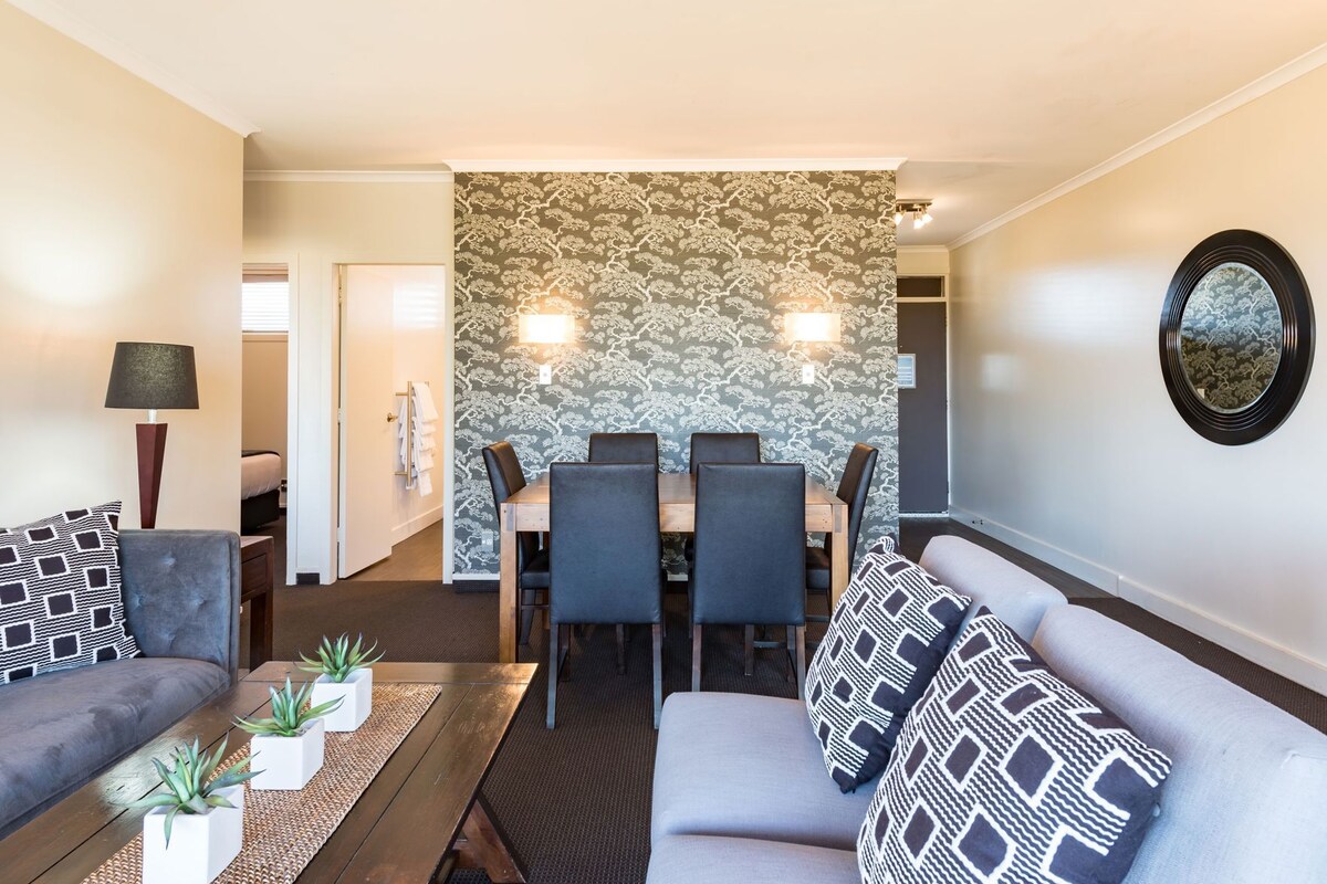Un salon moderne avec un coin repas, comprenant un canapé, un fauteuil, une table à manger et des chaises.