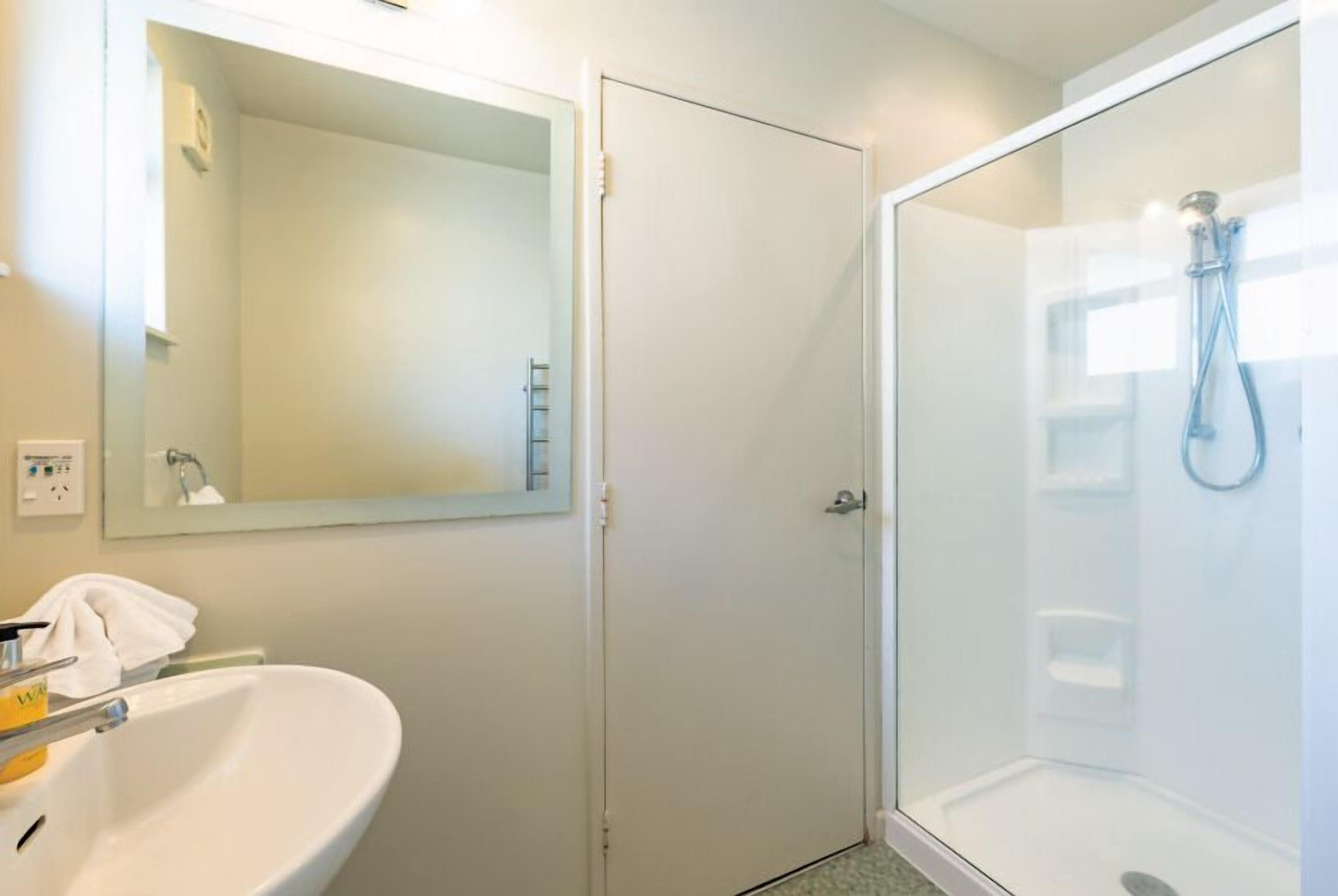 A bathroom with a white sink, a mirror, and a glass-enclosed shower.