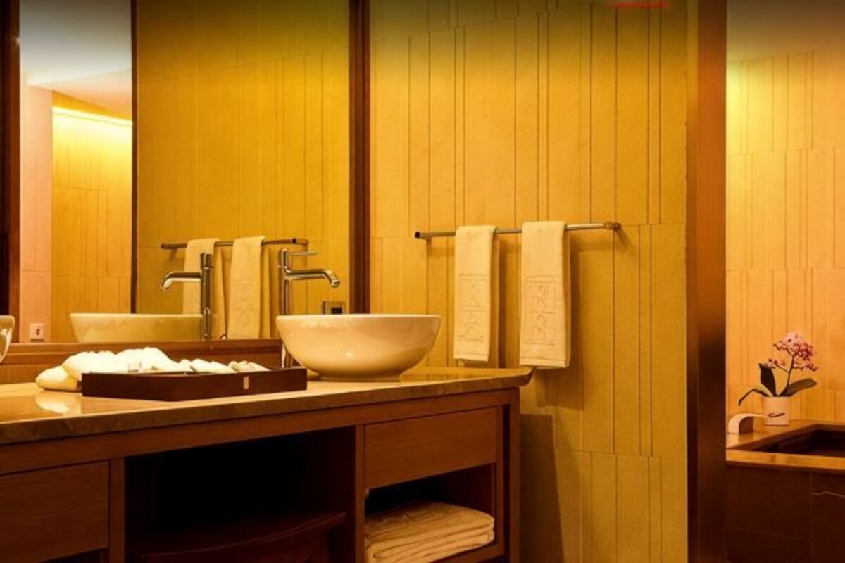 A bathroom with wooden paneling, a sink with a basin, a mirror, and towels on a rack.