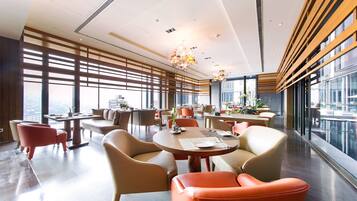 A modern dining area with high ceilings, large windows, and contemporary furniture.