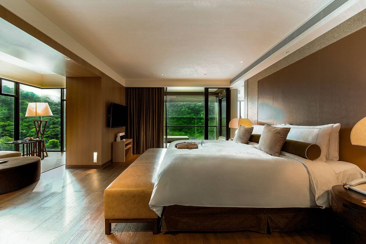 Um quarto espaçoso com uma cama grande, uma televisão e uma escrivaninha.