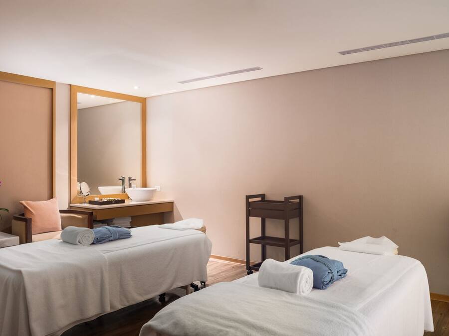 A hotel room with two beds, a sitting area, a vanity with a mirror, and a small desk.