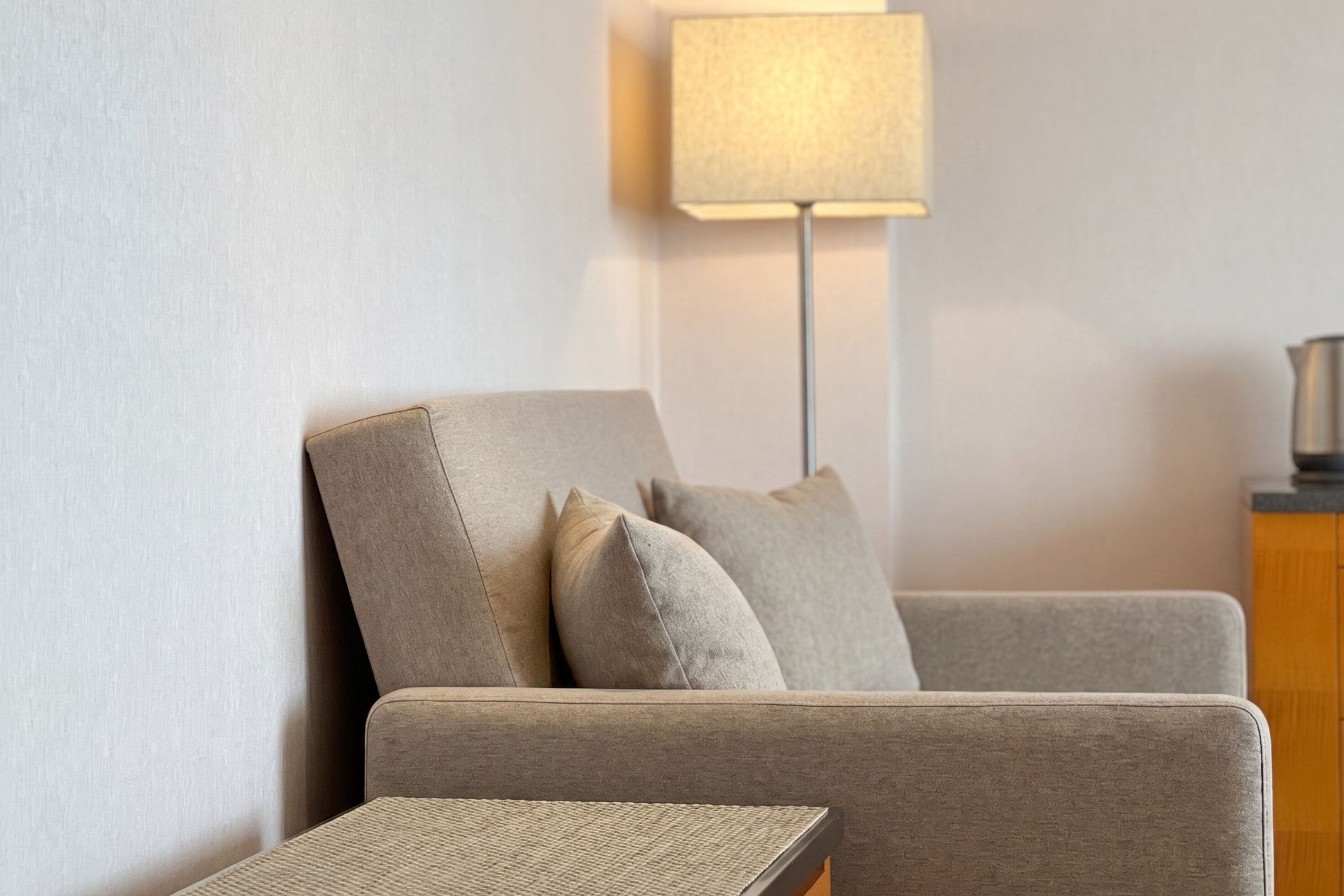 Ein modernes Wohnzimmer mit einer Couch, einem kleinen Beistelltisch und einer Stehlampe.