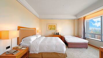 A hotel room with two beds, a desk with a telephone, a lamp, and a painting on the wall.