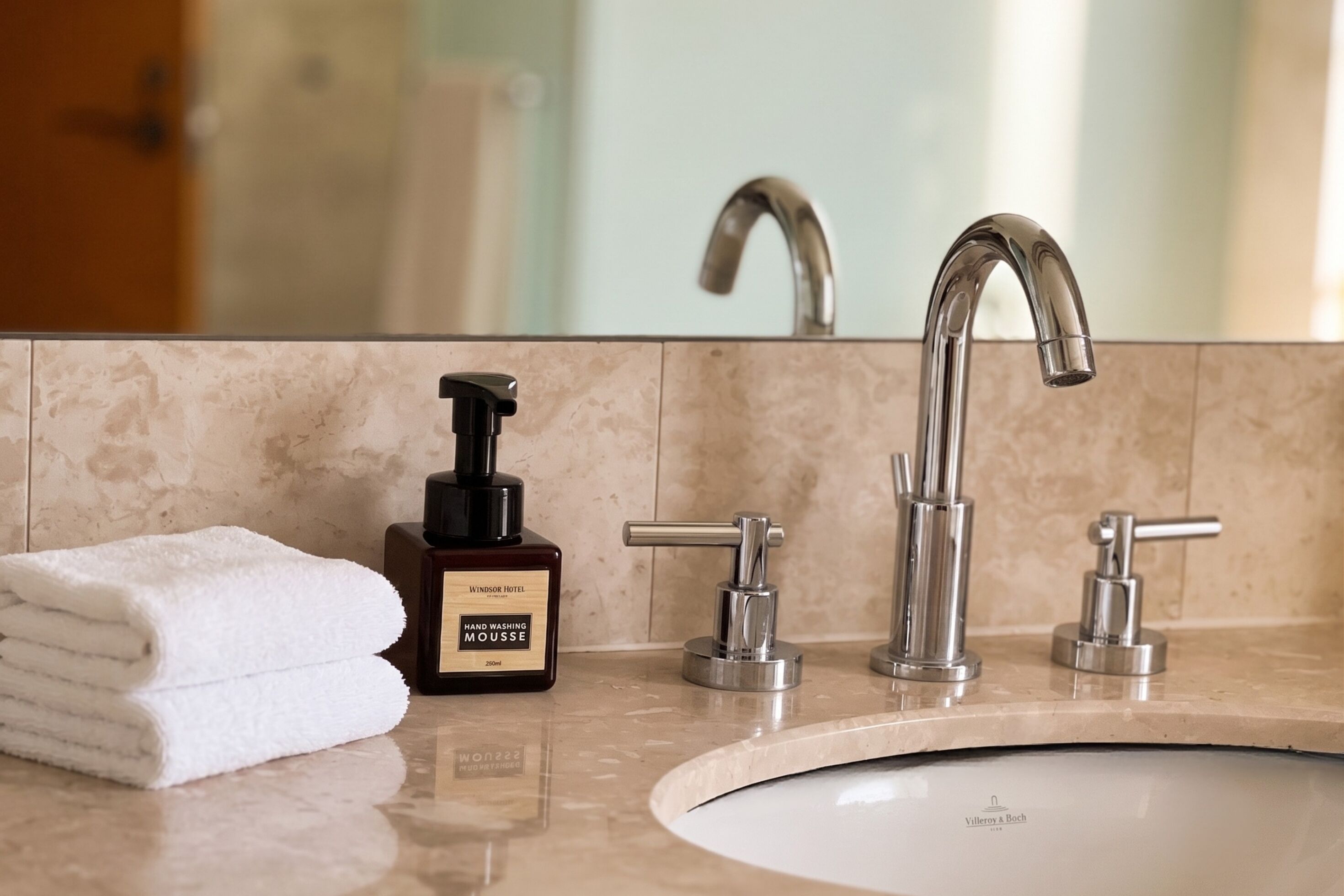 Un baño con lavamanos, dispensador de jabón y toalla.