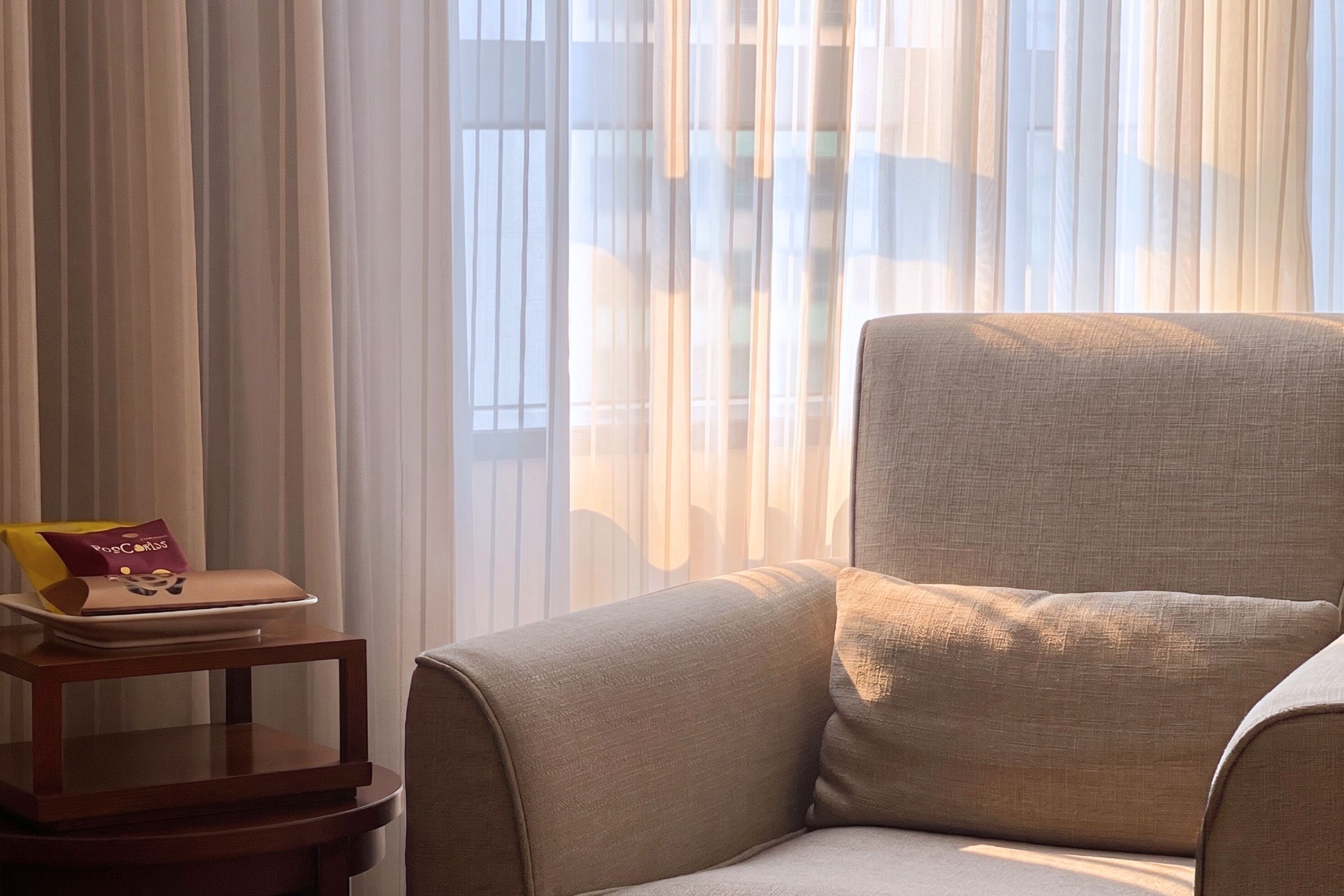 Una habitación con un ventanal grande, una silla, una mesita y un bolso sobre la mesa.