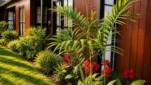 A building with a wooden facade, large windows, and a well-maintained garden with various plants and flowers. - Teal Motor Lodge (Gisborne)
