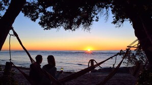 A hammock on a beach with a sunset in the background. - Teal Motor Lodge (Gisborne)