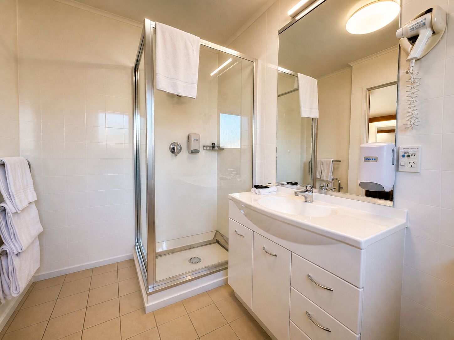 A modern bathroom with a glass shower enclosure, a white sink with a mirror, and a towel rack.