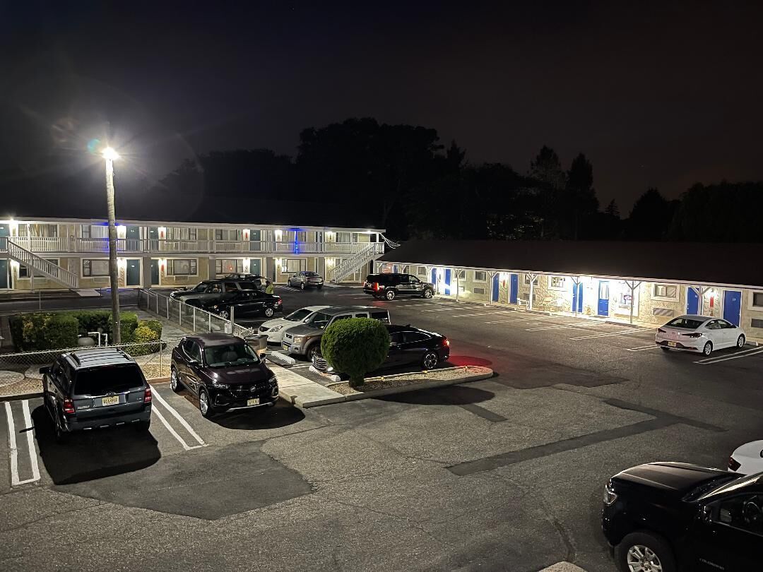 A parking lot with several cars, a building with multiple doors, and a staircase leading to an upper level.