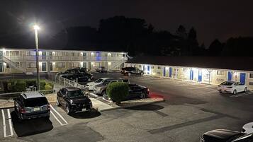 A parking lot with several cars, a building with multiple doors, and a staircase leading to an upper level.
