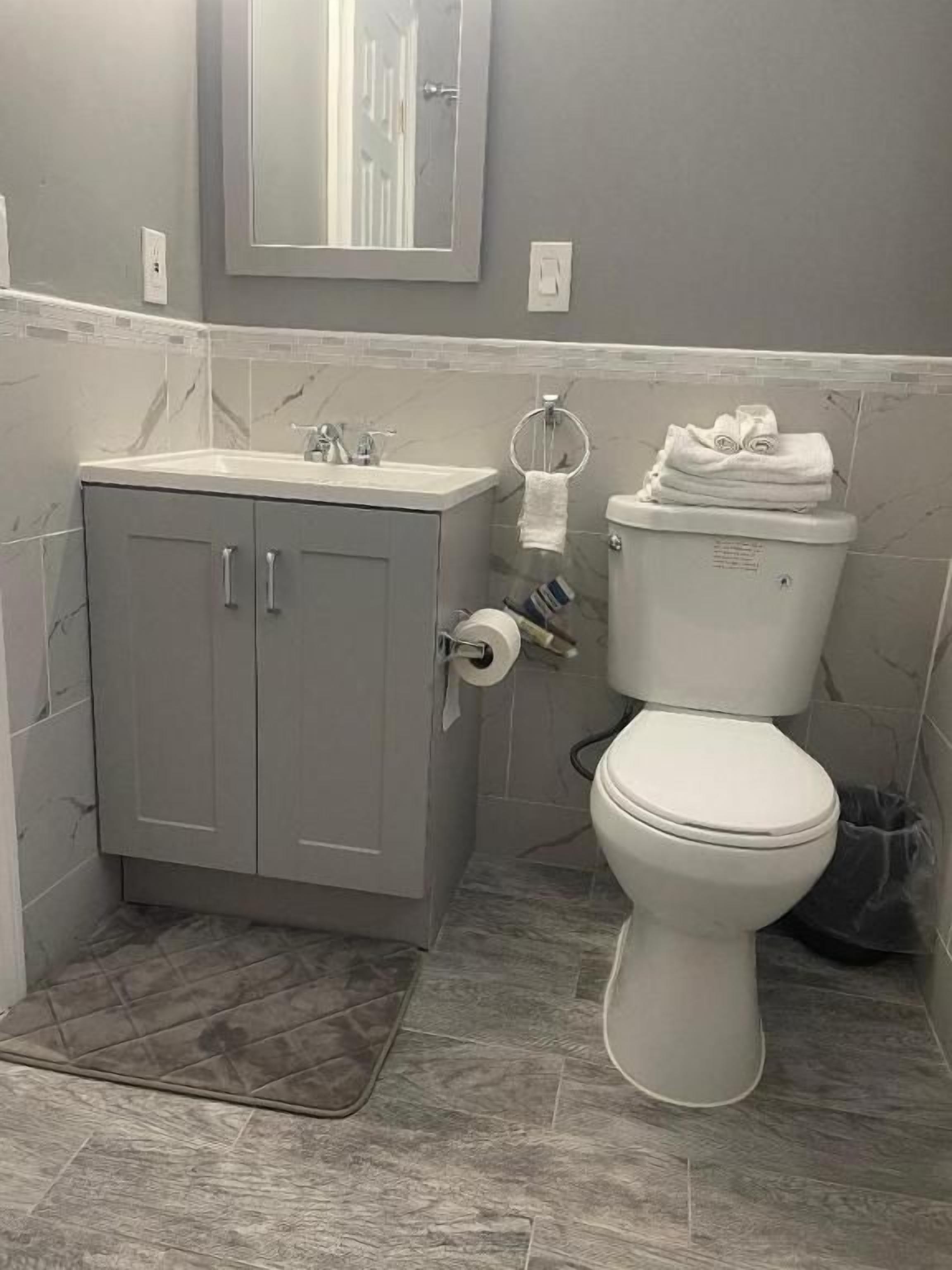 A bathroom with a toilet, sink, and mirror.