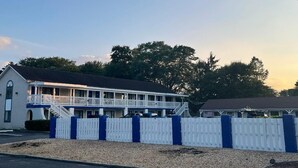 Ein Motel mit zweistöckiger Bauweise, einem überdachten Balkon und einem eingezäunten Vorgarten.