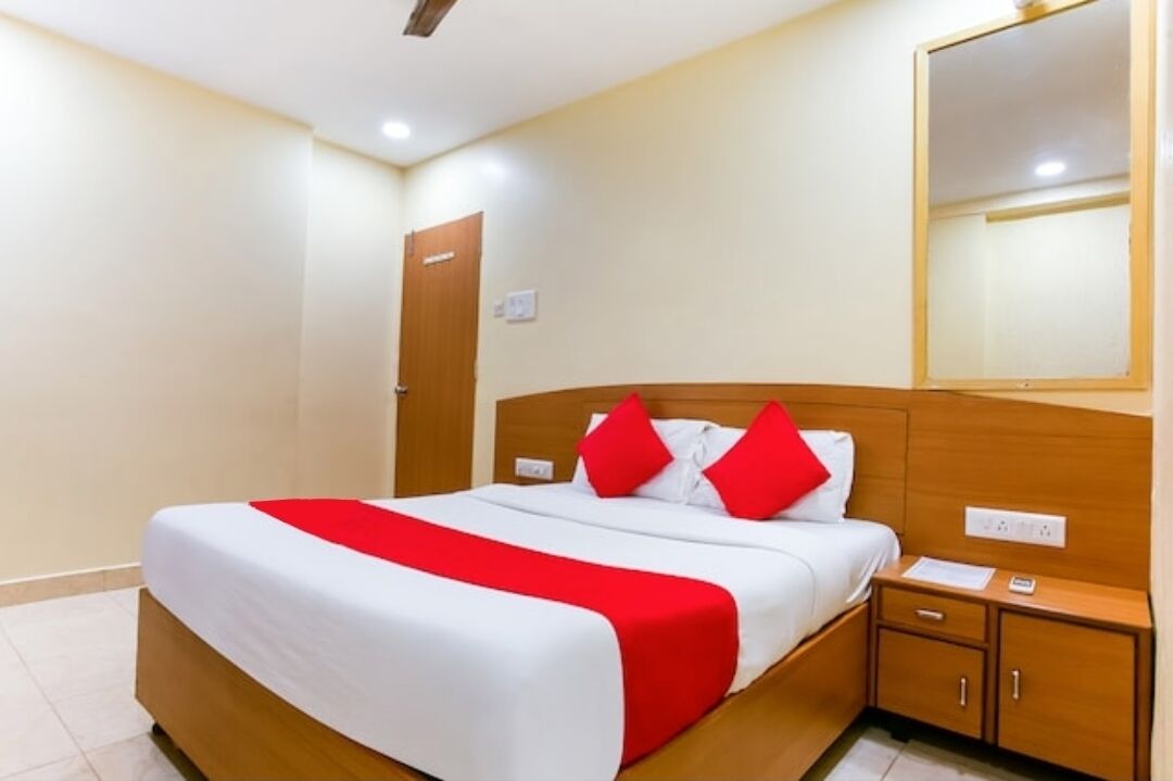 Una habitación de hotel con una cama, una mesita de noche, un espejo y una puerta.