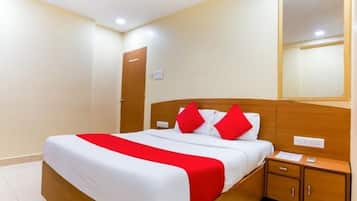 Una habitación de hotel con una cama, una mesita de noche, un espejo y una puerta.