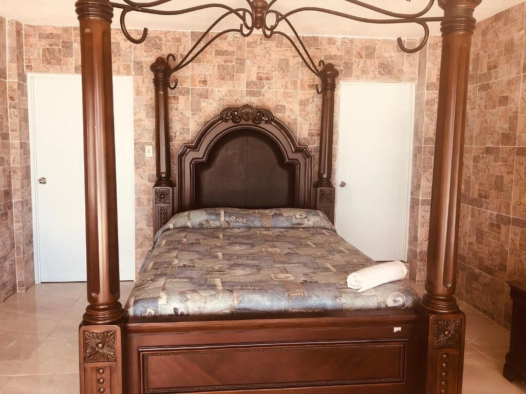 A four-poster bed with a dark headboard and a patterned bedspread.