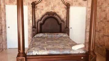 A four-poster bed with a dark headboard and a patterned bedspread.