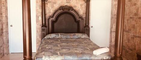 A four-poster bed with a dark headboard and a patterned bedspread.