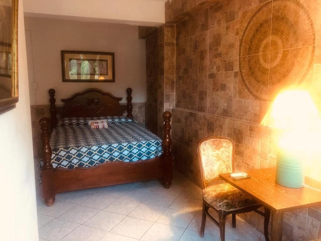 Un dormitorio con una cama de madera, una silla, una mesa y una pared con un diseño circular.