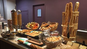 Ein Buffet mit verschiedenen Speisen, darunter Brot, Gebäck und Obst.