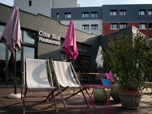 Mesa al aire libre con sombrillas, una planta en maceta y un edificio con un letrero que dice "Côté Sud Restaurant".