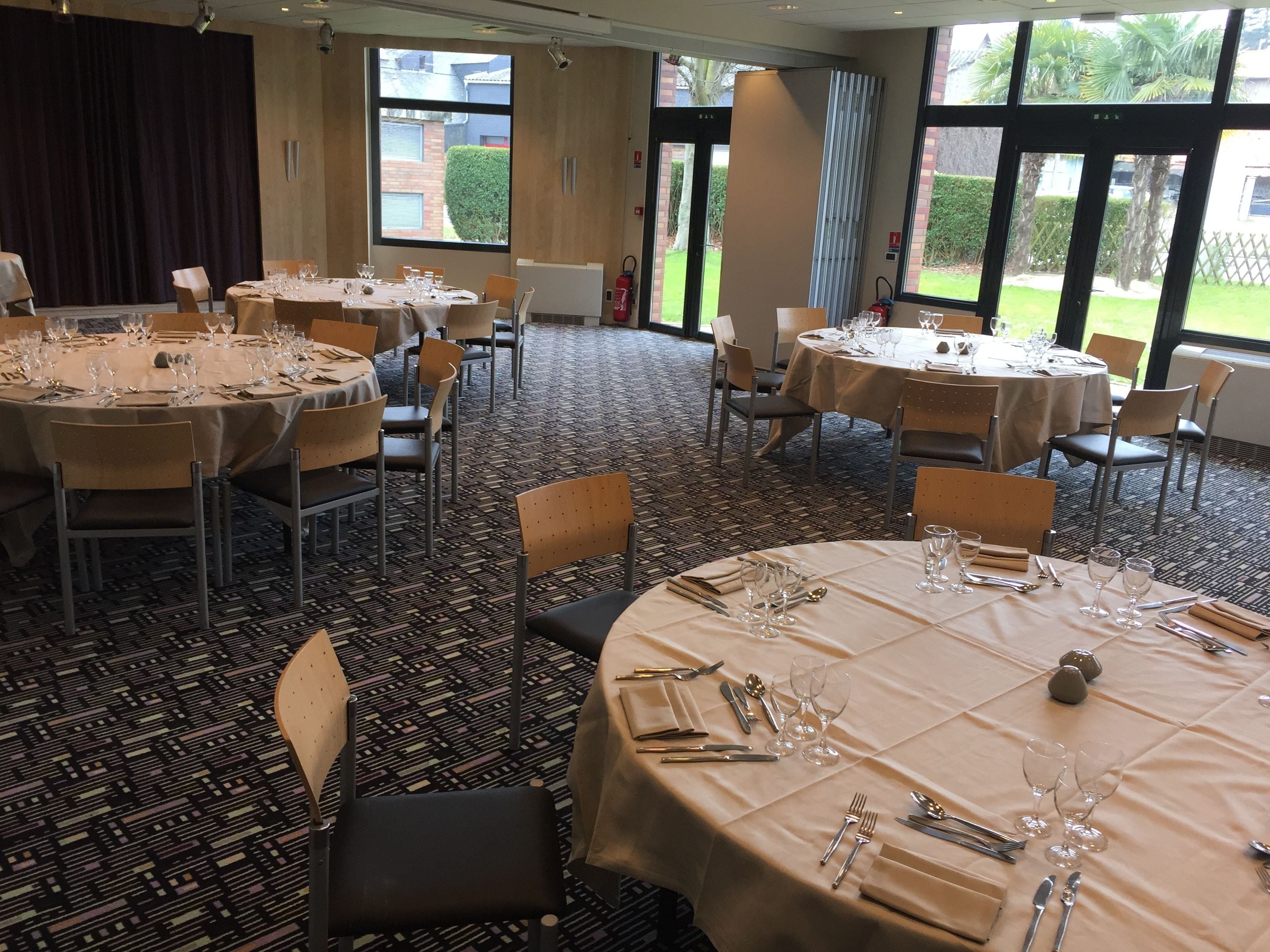 A conference room with round tables set for dining, equipped with chairs and dining essentials.