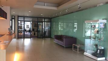 A modern lobby with a reception desk, a glass display case, a purple sofa, and a glass partition.