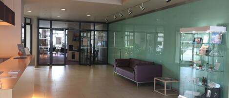 A modern lobby with a reception desk, a glass display case, a purple sofa, and a glass partition.
