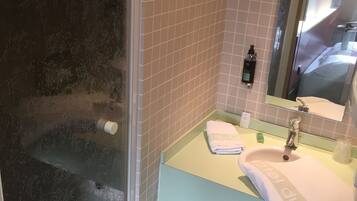 Un baño con cabina de ducha de vidrio, lavabo con espejo y retrete.