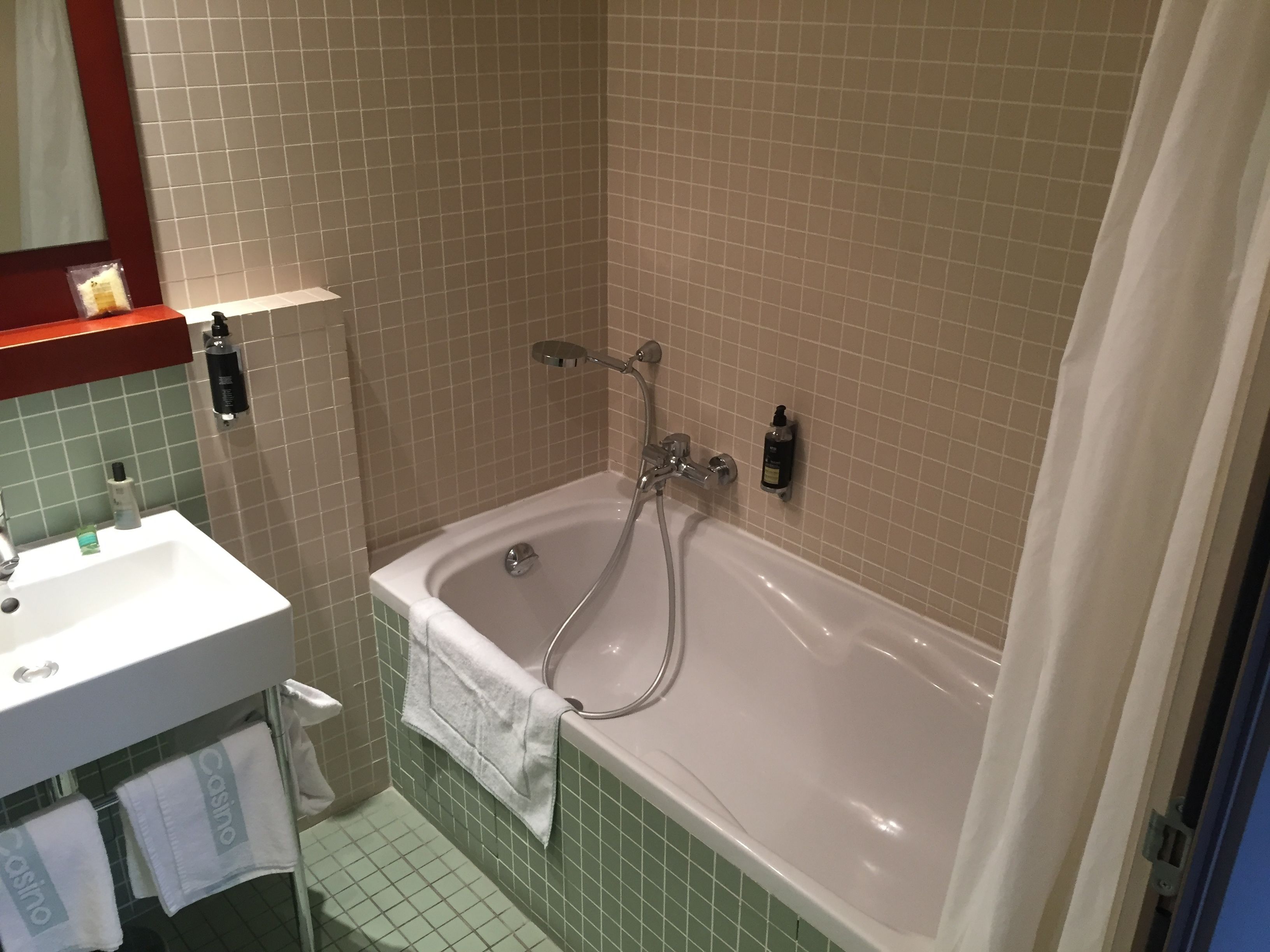 A bathroom with a bathtub, a sink, and a mirror.