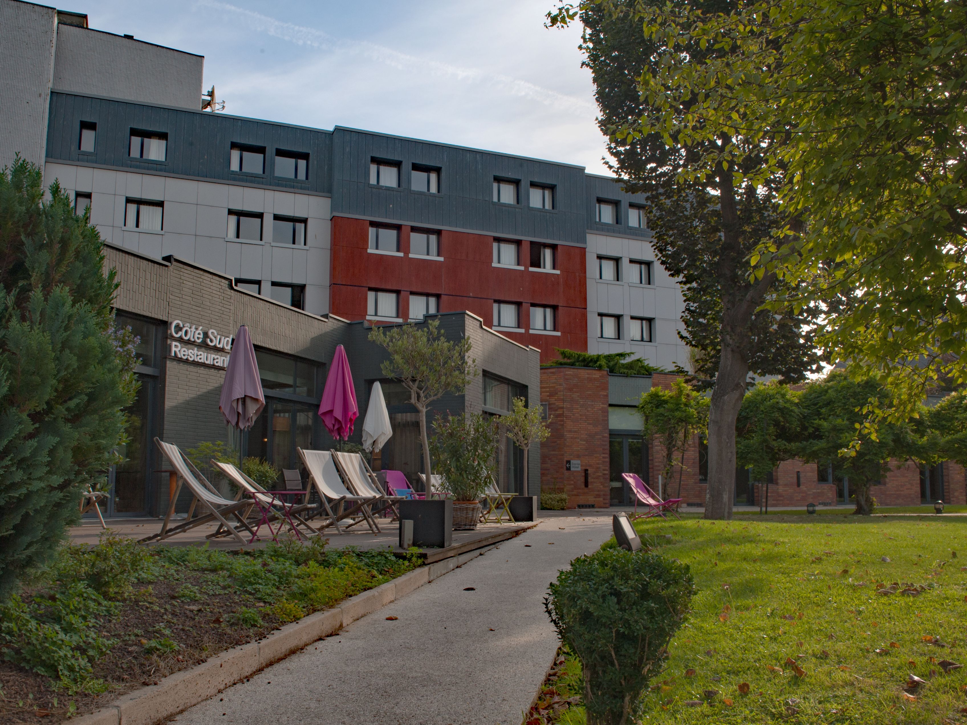 Un bâtiment moderne qui abrite un restaurant appelé « Côté Sud » et dispose d’une terrasse avec des parasols.