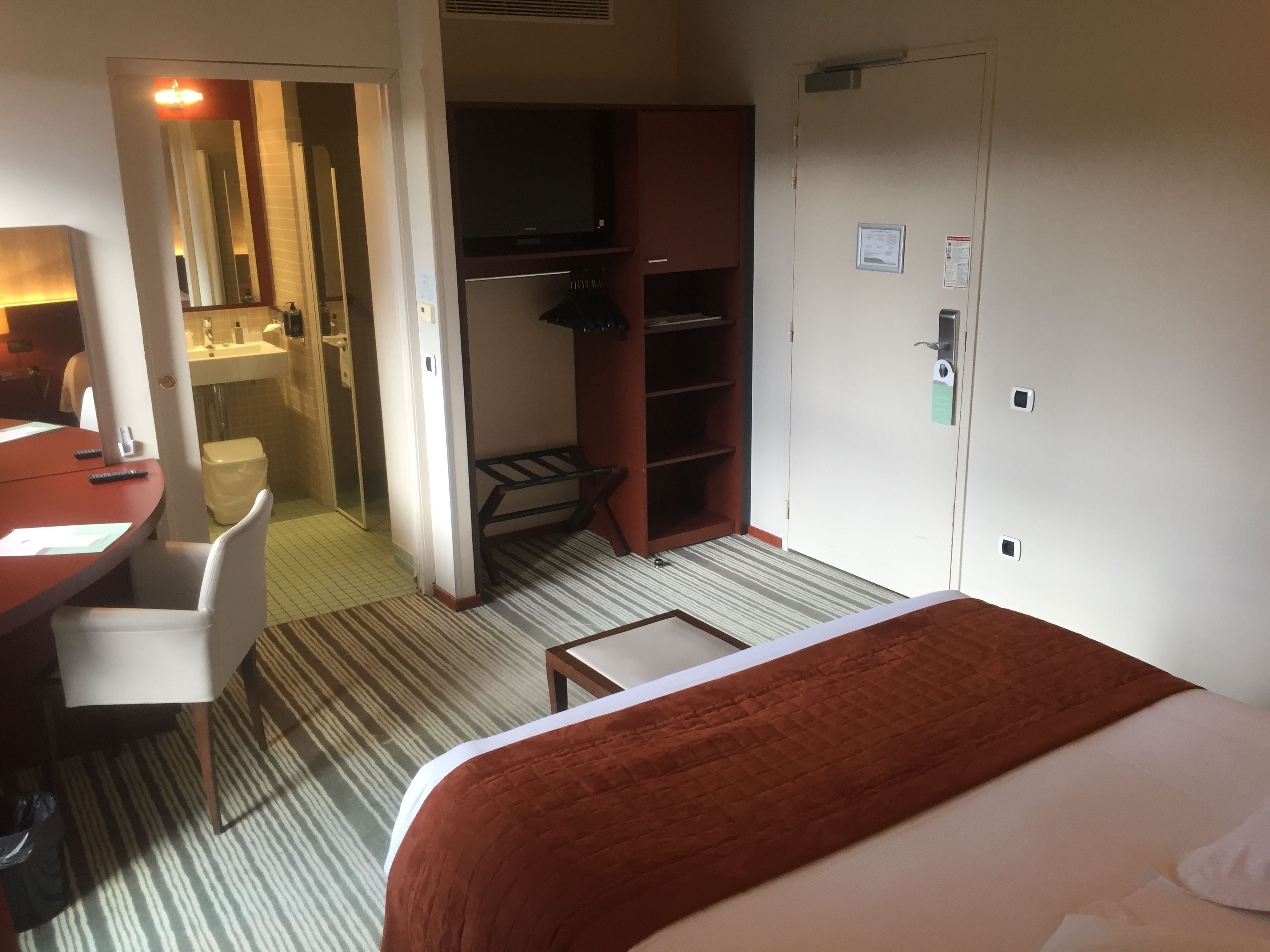 Une chambre d’hôtel comprenant un lit, un bureau avec une chaise, une armoire, une télévision et une salle de bain.