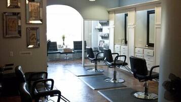 Ein Salon mit mehreren Sitzgelegenheiten, einer Rezeption und großen Deckenleuchten.